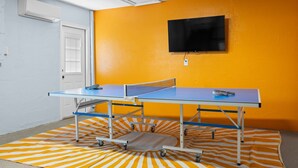 A room with a ping pong table, a television on the wall, and a door with blinds. - Sand Volleyball Pool Hot Tub 4BR Seminole FL (Seminole)