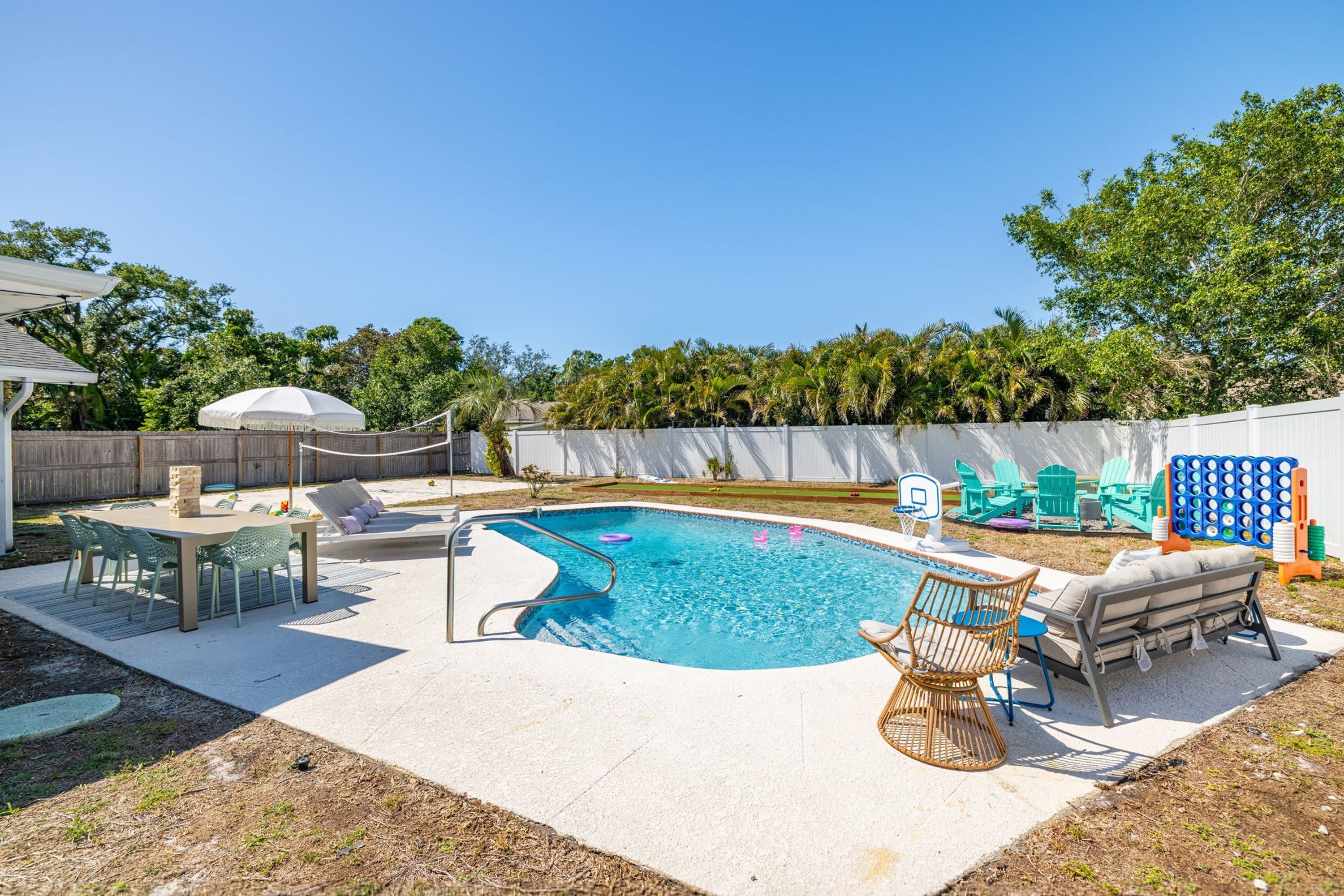 A backyard with a swimming pool, a dining area, and a play area.