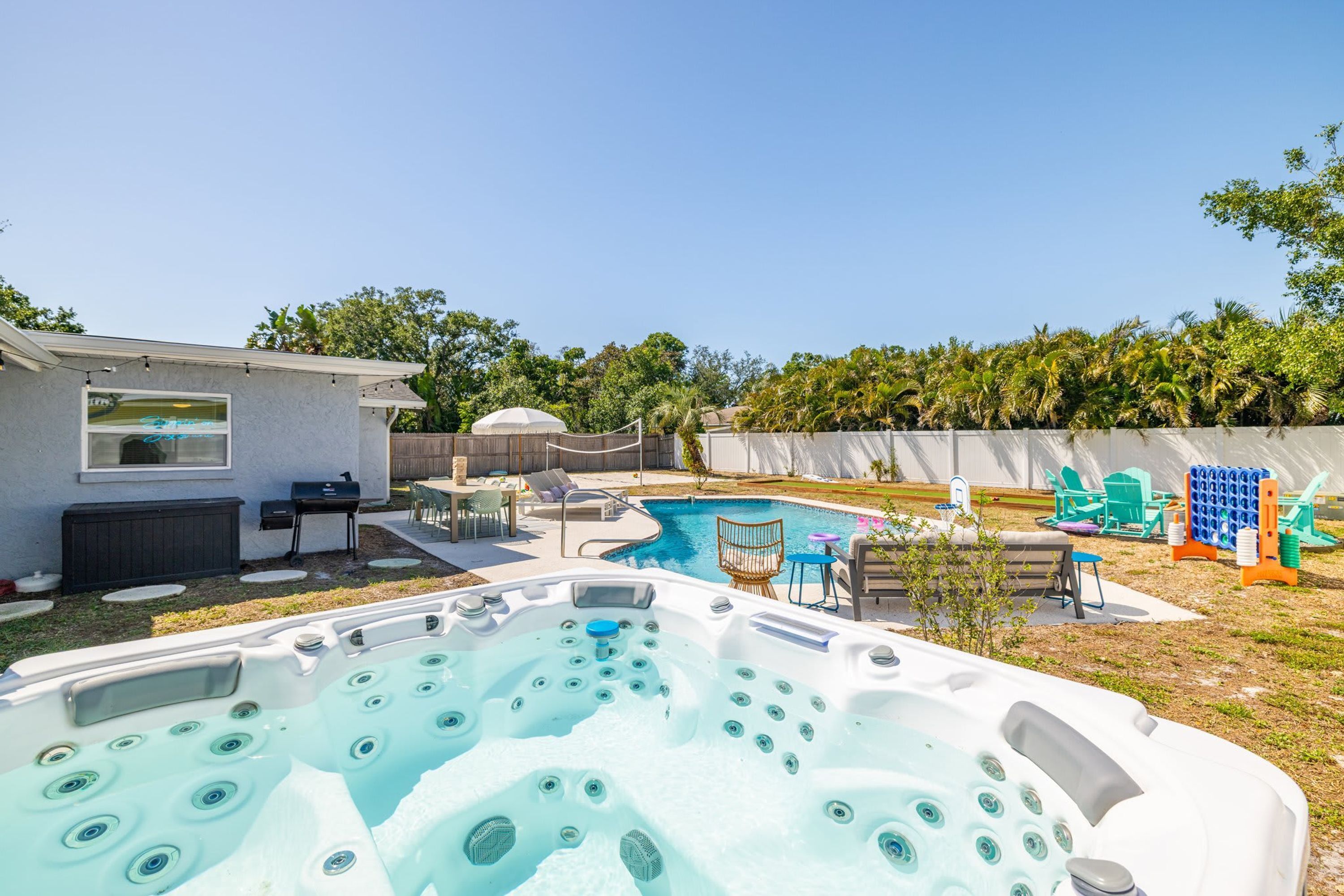 Um quintal com piscina, banheira de hidromassagem e móveis de jardim.