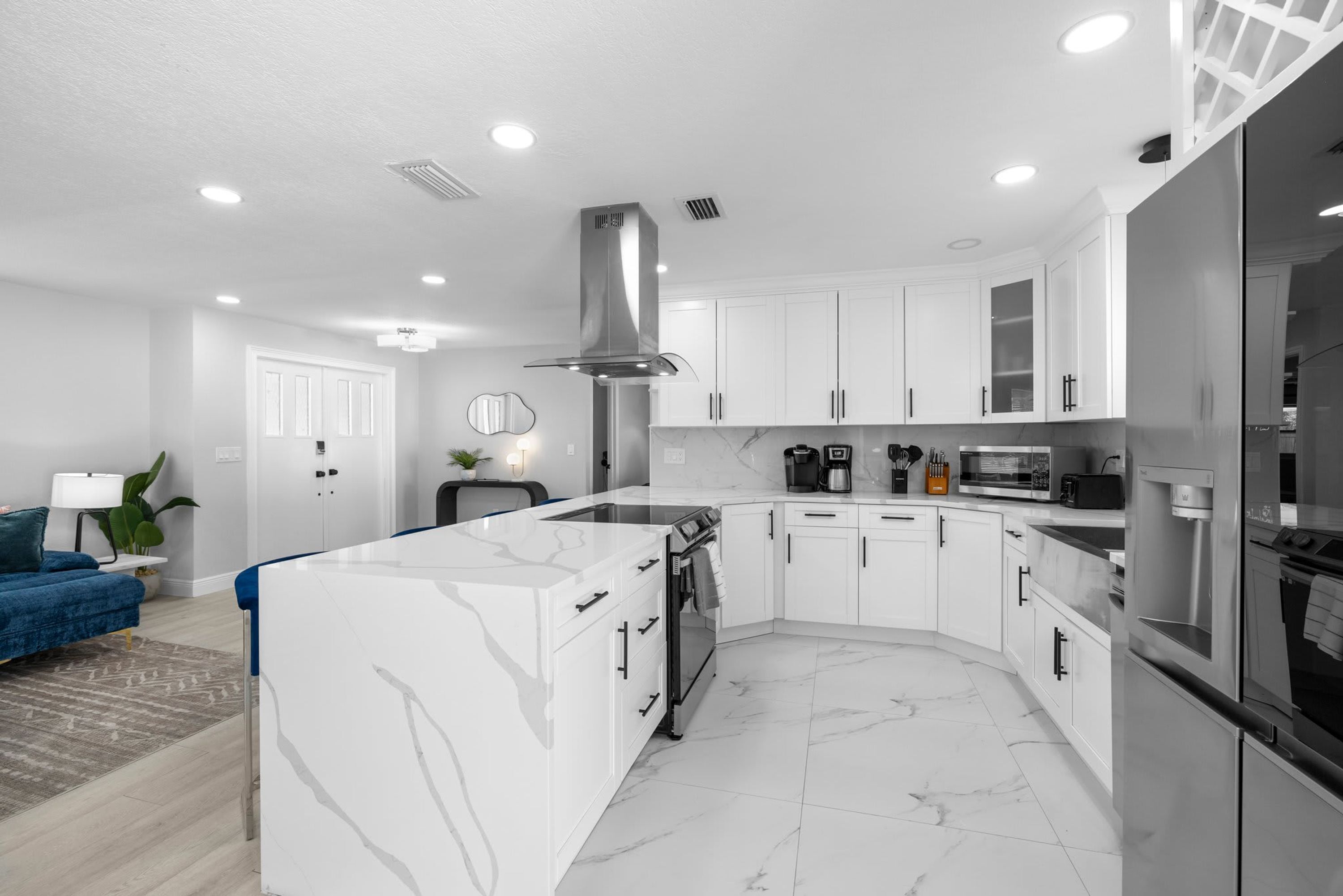 Una cocina moderna con armarios blancos, encimera de mármol y electrodomésticos de acero inoxidable.