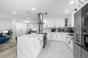 Une cuisine moderne avec des meubles blancs, un plan de travail en marbre et des appareils électroménagers en acier inoxydable.