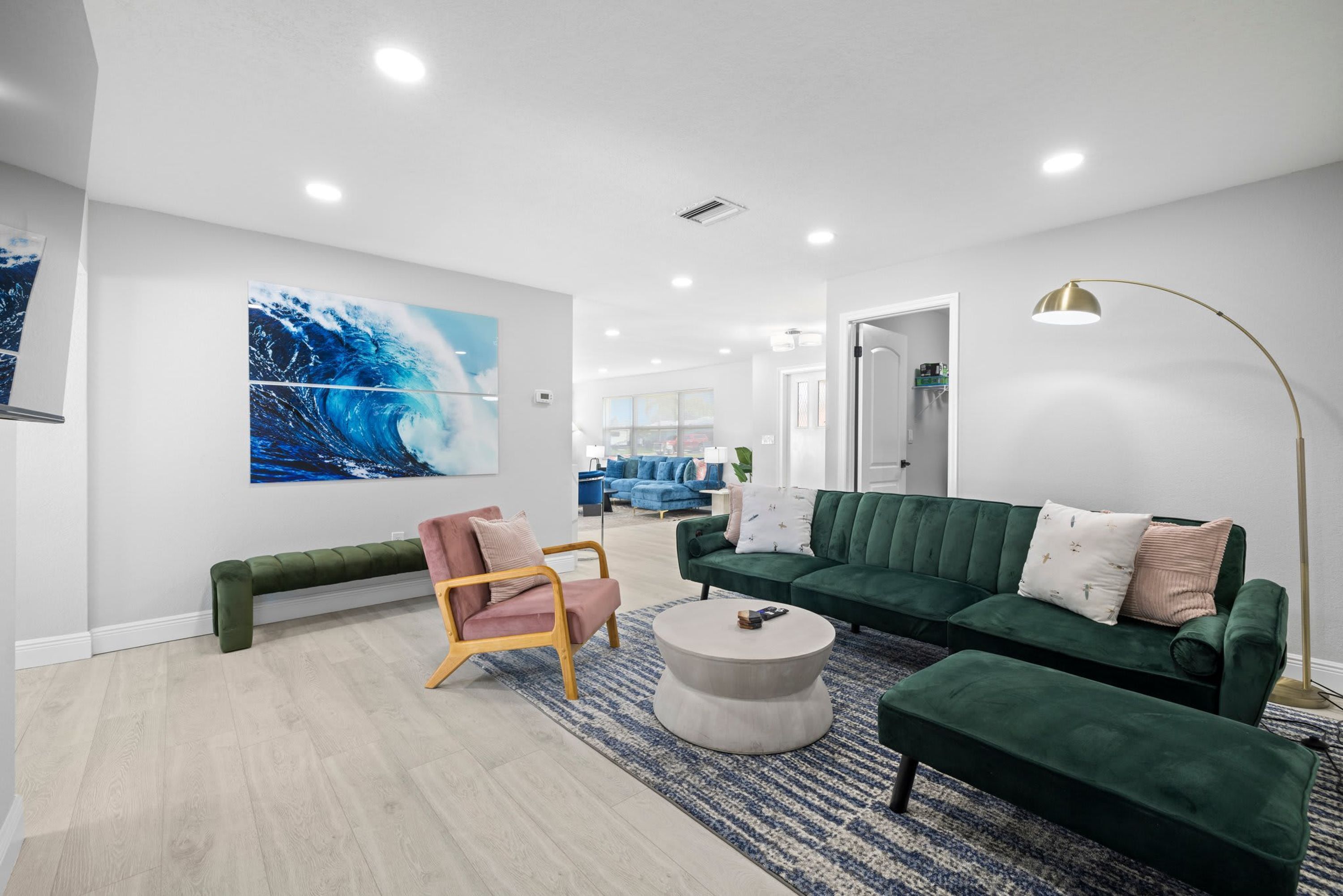 A modern living room with a green sofa, a pink chair, and a round coffee table.