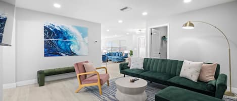 Una sala de estar moderna con un sofá verde, un sillón rosa y una mesa de centro redonda.