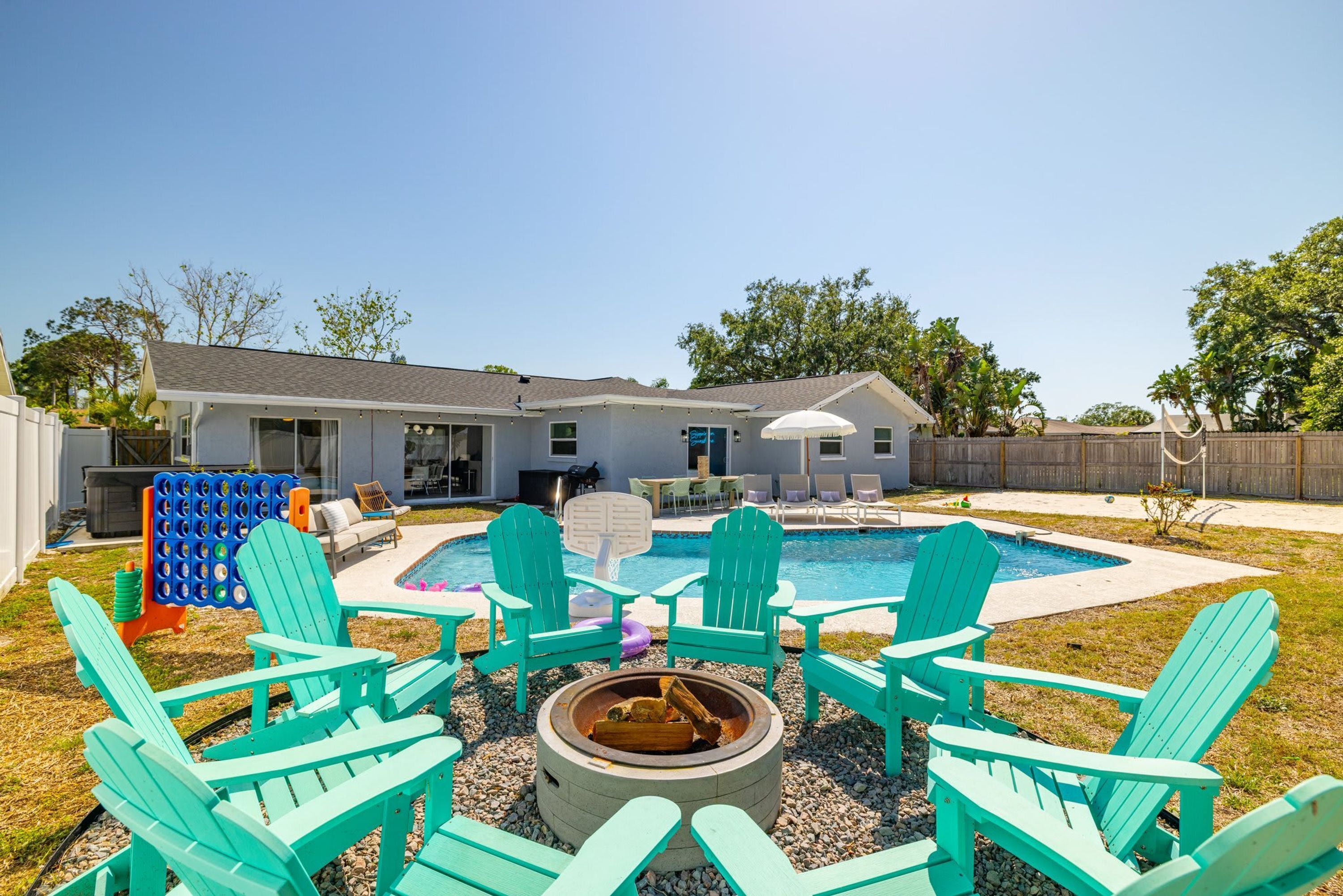 Un patio trasero con piscina, mobiliario exterior y una chimenea.