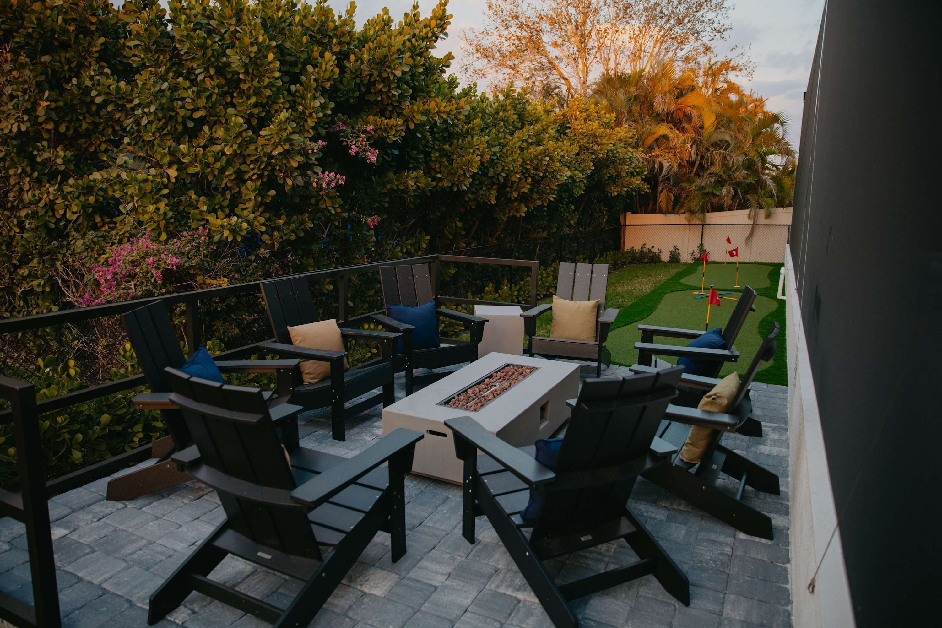 An outdoor patio with black chairs, a rectangular table, and a fire pit.