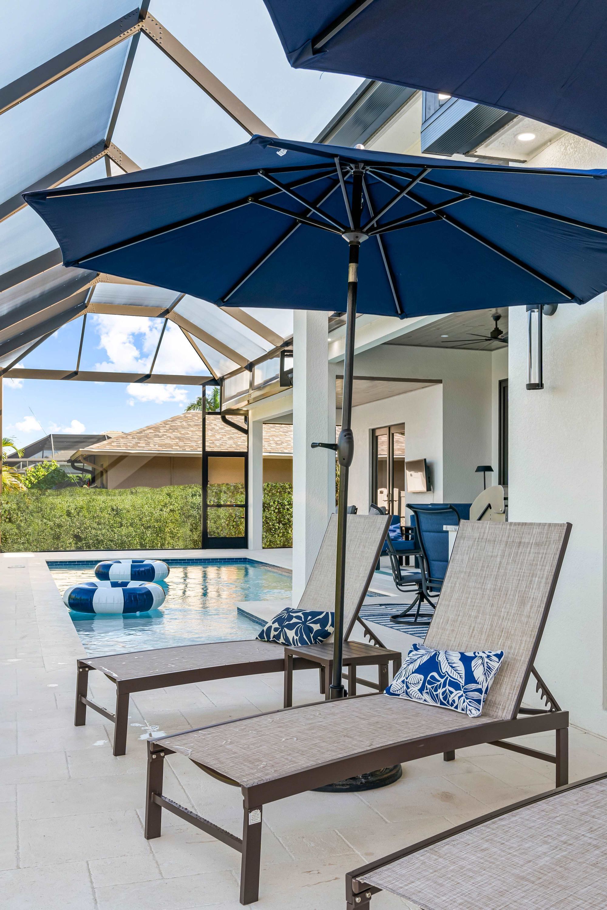A poolside area with lounge chairs and umbrellas, a pool, and a view of the surrounding landscape.