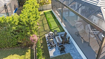 A rooftop patio with a putting green, outdoor seating, and a glass enclosure.