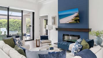 A modern living room with a large sofa, a fireplace, and a TV mounted on the wall.