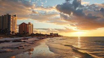 A beach with buildings in the background and a sunset.