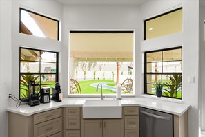 A kitchen with a large window, a sink, and a dishwasher. - The Lazy Palm Private Lazy River Pickleball (Glendale)