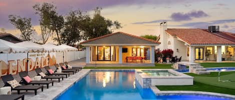 A residential property with a swimming pool, outdoor seating, and a well-maintained lawn.