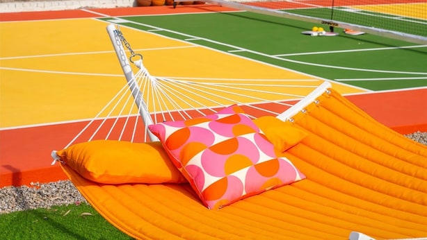 A basketball court with a hammock and pillows, surrounded by trees and a wall with colorful designs. - The Lazy Palm Private Lazy River Pickleball (Glendale)