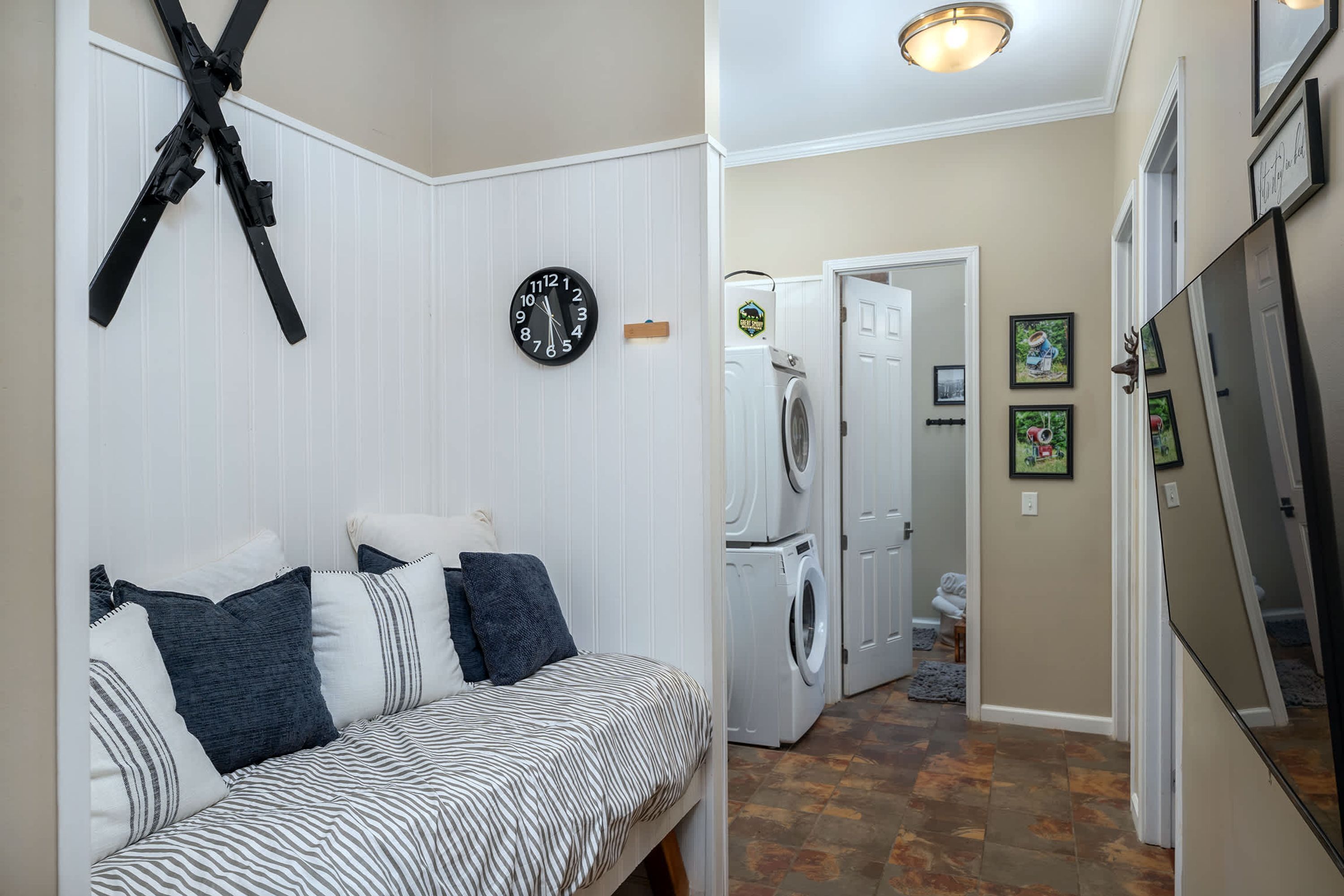 A compact living space with a bed, a clock, a washing machine, and a refrigerator.