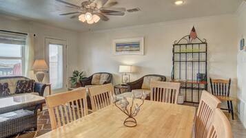 A dining area with a wooden table and chairs, a ceiling fan, and a view of the outdoors.