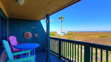 Eine überdachte Veranda mit Blick auf einen Strand und ein Haus.