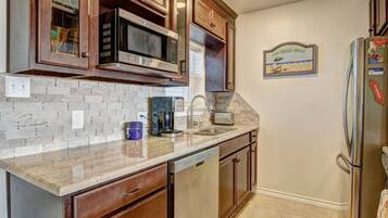 A kitchen with wooden cabinets, a microwave, a coffee maker, and a refrigerator.