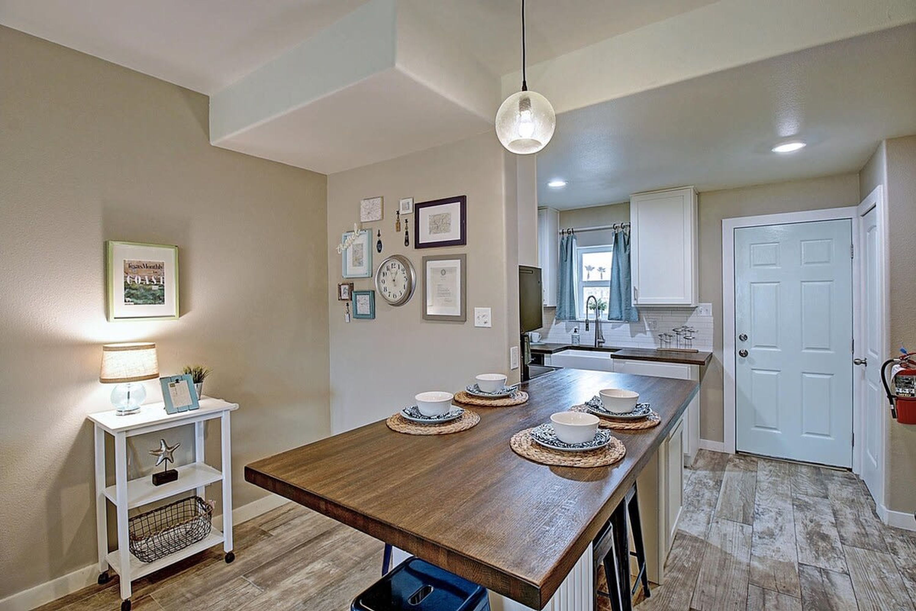 A kitchen with a wooden island, white cabinets, and a hanging light fixture.