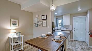 A kitchen with a wooden island, white cabinets, and a hanging light fixture.