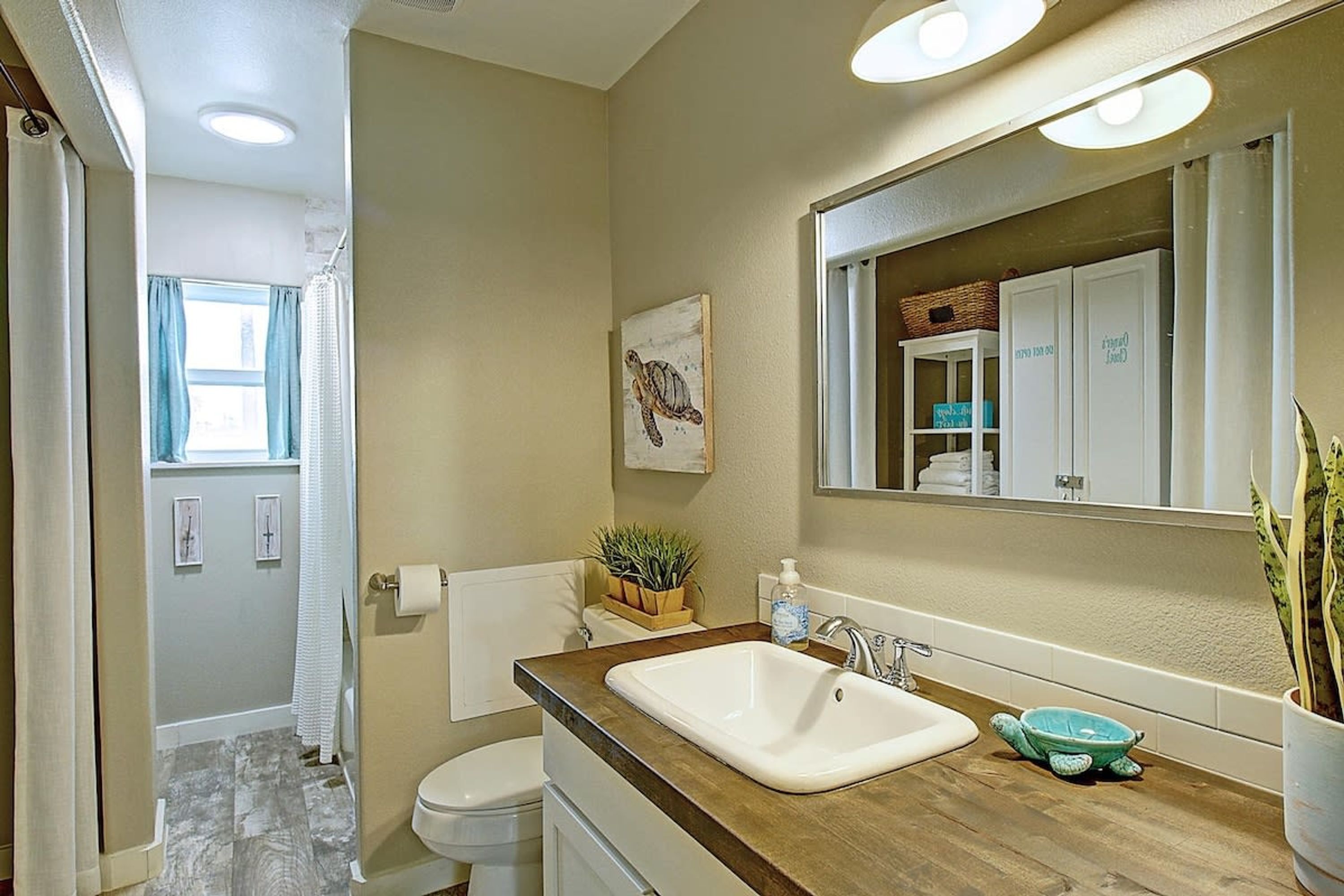 A bathroom with a wooden vanity, a white sink, a mirror, and a towel rack.