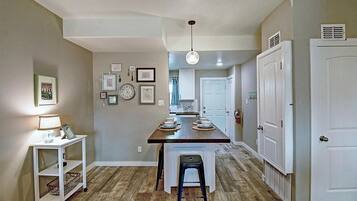 A kitchen with a central island, white cabinetry, and a dining area with a chair.