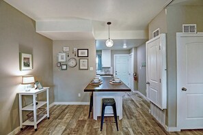 Una cocina con una isla central, muebles blancos y un comedor con una silla.