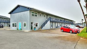 A motel with a two-story structure, a blue exterior, and a parking lot with several cars.