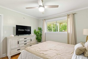 A bedroom with a bed, a television on a dresser, a ceiling fan, a window with curtains, and a plant. - 2 Miles to Beach Pool Cabana Pool Table (Deerfield Beach)