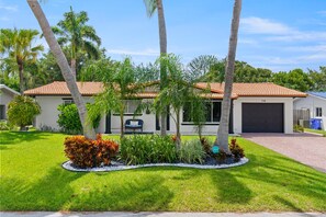 A residential house with a tiled roof, a garage, and a well-maintained lawn with various plants. - 2 Miles to Beach Pool Cabana Pool Table (Deerfield Beach)