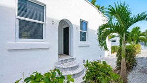 Um edifício branco com fachada curva, uma porta e uma janela com persianas.