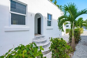 A white building with a curved facade, a door, and a window with blinds. - Pineapple Paradise 2 13 min to Beach Fire Pit (Sarasota)