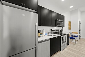 A modern kitchen with a refrigerator, microwave, stove, and sink. - Pineapple Paradise 2 13 min to Beach Fire Pit (Sarasota)