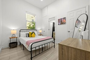 A bedroom with a bed, bedside lamps, a window, a door, and a mirror. - Pineapple Paradise 2 13 min to Beach Fire Pit (Sarasota)