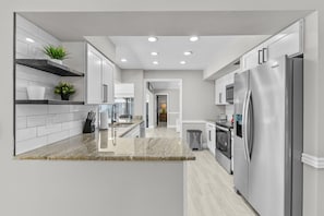 A modern kitchen with a central island, stainless steel appliances, and a view into the dining area. - Sleeps 8 Tiki Bar Pool Hot Tub Fire Pit (Tampa)
