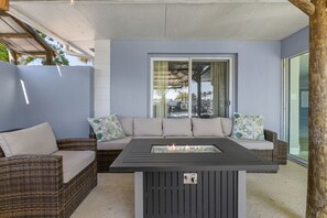 A covered outdoor seating area with a fire feature in the center, a window with curtains, and a view of the outdoors. - Sleeps 8 Tiki Bar Pool Hot Tub Fire Pit (Tampa)