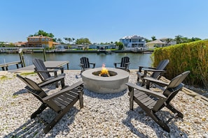 A waterfront outdoor seating area with a fire pit, surrounded by Adirondack chairs, overlooking a marina with boats and houses. - Sleeps 8 Tiki Bar Pool Hot Tub Fire Pit (Tampa)