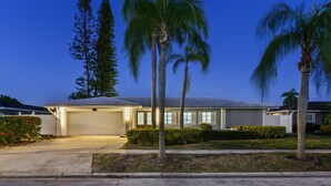A residential house with a garage, palm trees, and a clear sky. - Sleeps 8 Tiki Bar Pool Hot Tub Fire Pit (Tampa)
