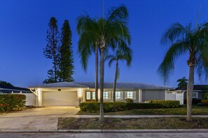 A residential house with a garage, palm trees, and a clear sky. - Sleeps 8 Tiki Bar Pool Hot Tub Fire Pit (Tampa)