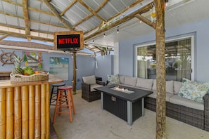 Zona d'estar a l'aire lliure amb barra, una xemeneia i un cartell que indica servei Netflix.