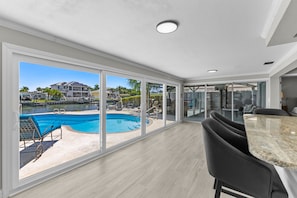 A modern living room with a large sliding glass door leading to a pool area. - Sleeps 8 Tiki Bar Pool Hot Tub Fire Pit (Tampa)