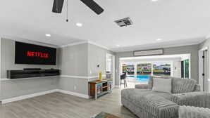 A living room with a flat-screen TV, a pool view, and a cozy seating area. - Sleeps 8 Tiki Bar Pool Hot Tub Fire Pit (Tampa)