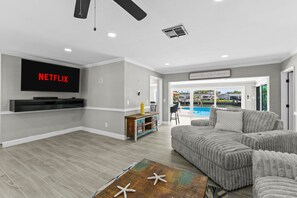 A living room with a flat-screen TV, a pool view, and a cozy seating area. - Sleeps 8 Tiki Bar Pool Hot Tub Fire Pit (Tampa)