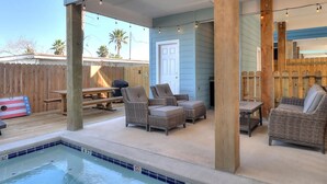 A poolside area with a hot tub, lounge chairs, and a wooden deck. - Highway 9 Private Pool BBQ (Port Aransas)
