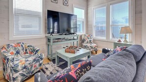 A living room with a sofa, armchair, television, and a coffee table. - Highway 9 Private Pool BBQ (Port Aransas)