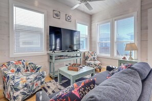 A living room with a sofa, armchair, television, and a coffee table. - Highway 9 Private Pool BBQ (Port Aransas)