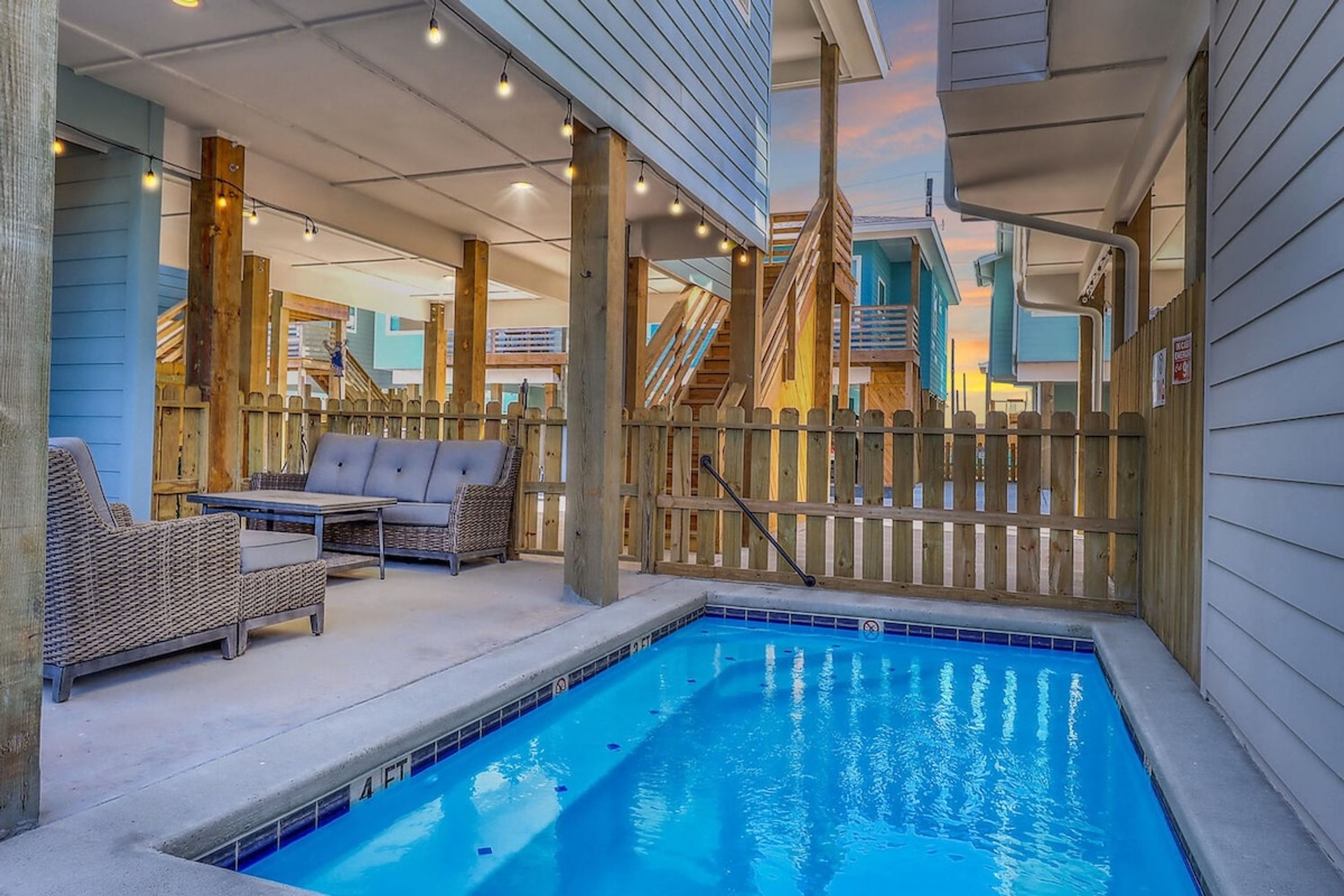Ein Poolbereich mit Holzterrasse, Liegestühlen und einer überdachten Sitzgelegenheit.