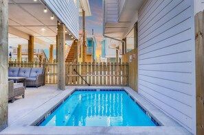 A pool area with a wooden deck, a covered seating area, and a view of the sky. - Highway 9 Private Pool BBQ (Port Aransas)