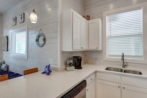 A kitchen with white cabinets, a dishwasher, a coffee maker, and a sink. - Highway 9 Private Pool BBQ (Port Aransas)