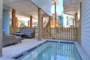 Área da piscina com profundidade de 1,2 metros, deck de madeira e mobiliário para área externa.