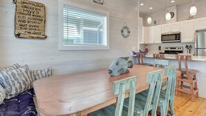 A dining area with a wooden table and chairs, a decorative fish sculpture, and a wall-mounted sign with text. - Highway 9 Private Pool BBQ (Port Aransas)
