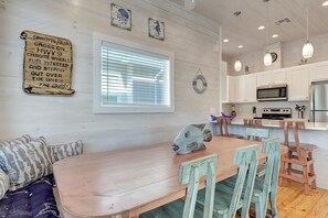 A dining area with a wooden table and chairs, a decorative fish sculpture, and a wall-mounted sign with text. - Highway 9 Private Pool BBQ (Port Aransas)